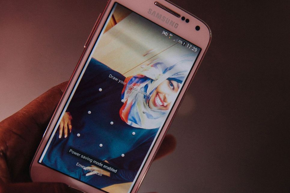 Eine Frau mit Kopftuch auf einem Handy Display.