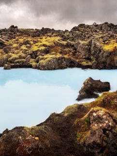 Hellblaues Wasser, umgeben von bräunlichen Felsen.