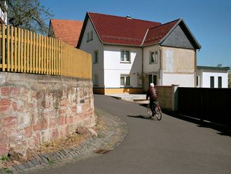 Sonnige Straßenkurve in einem Dorf mit Fahrradfahrer.