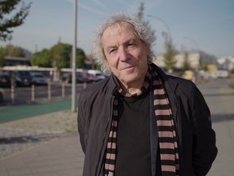 Andreas Knie auf dem Bürgersteig, im Hintergrund Stadt und ein grün markierter Fahrradweg.