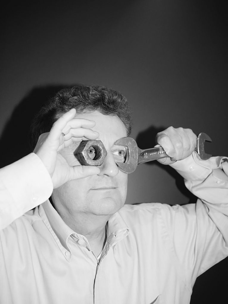 Wolfgang M. Heckl hält sich eine große Schraubenmutter und einen großen Schraubenschlüssel vor die Augen und schaut durch die Löcher hindurch.