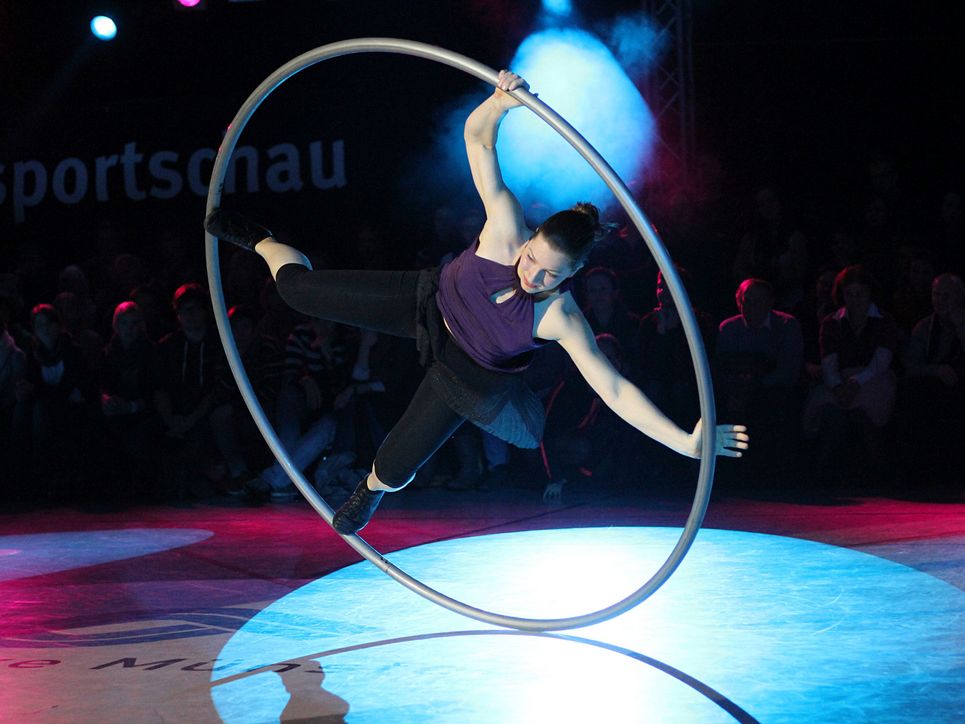 Frau rollt in einem großen Ring im Scheinwerferlicht.