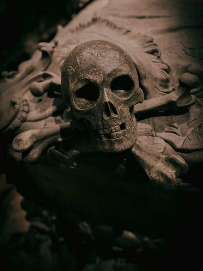 Detailaufnahme eines steinernen Totenkopfes mit gekreuzten Knochen