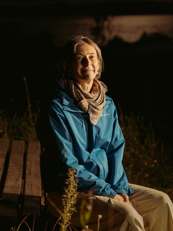 Marina Kahrmann, Projektleiterin vom Sternenpark-Projekt im Naturpark Nossentiner/Schwinzer Heide, sitzt auf einer Sternenbeobachtungsliege und schaut in die Kamera. Sie trägt eine blaue Outdoorjacke und ein Tuch um den Hals.