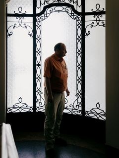 Historiker und Vampirforscher Dr. Peter Mario Kreuter Ein Mann steht im Profil vor einer hohen, ornamentierten Glastür mit schmiedeeisernen Verzierungen. Das Gegenlicht lässt ihn als Silhouette erscheinen. Der Mann ist der Wissenschaftler Peter Mario Kreuter.