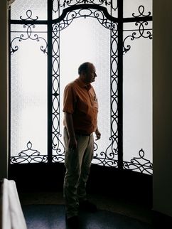 Historiker und Vampirforscher Dr. Peter Mario Kreuter Ein Mann steht im Profil vor einer hohen, ornamentierten Glastür mit schmiedeeisernen Verzierungen. Das Gegenlicht lässt ihn als Silhouette erscheinen. Der Mann ist der Wissenschaftler Peter Mario Kreuter.