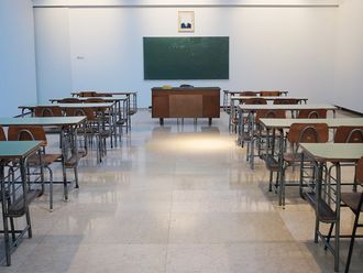 Tische und Stühle vor einer Tafel in einem leeren Klassenraum