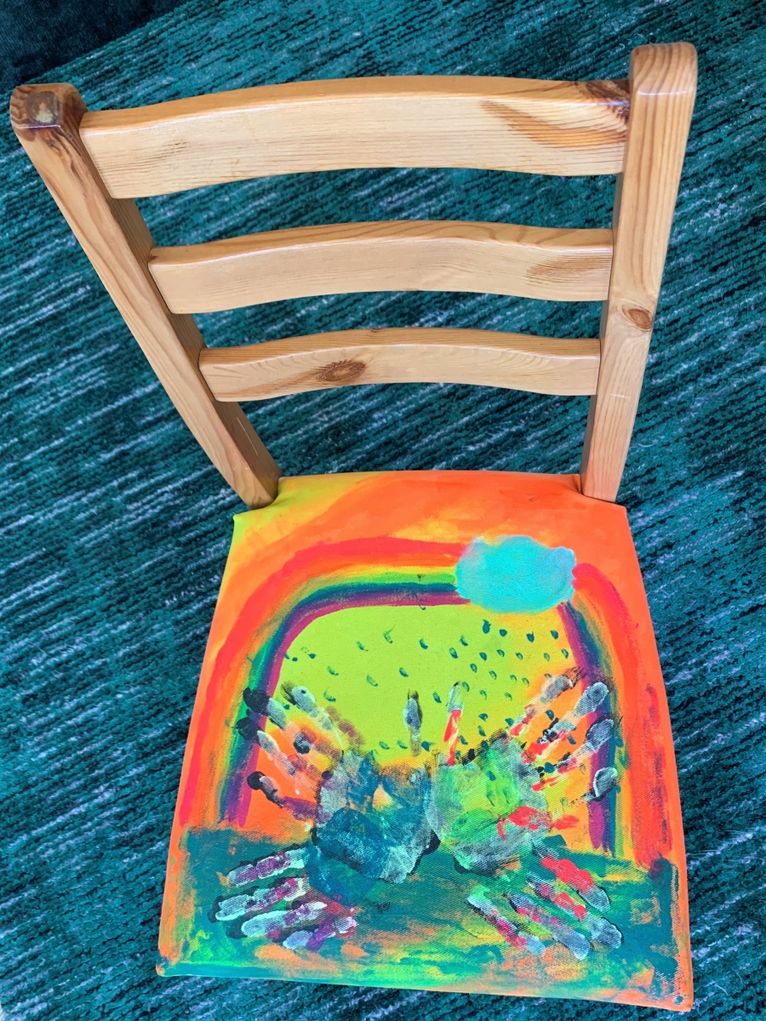 Stuhl mit bunt bemalter Sitzfläche.