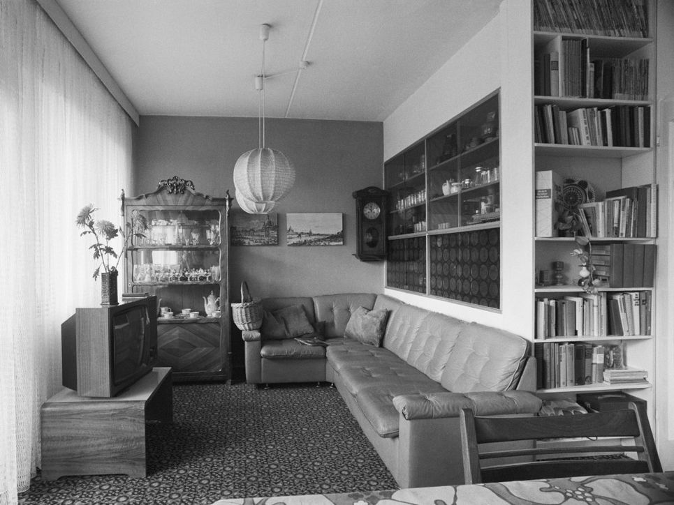 Ecksofa, Fernseher, Vitrinenschrank im Wohnzimmer des Wohnungstyps P2.