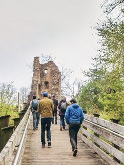Mehrere Personen gehen bergauf zu einer Ruine.