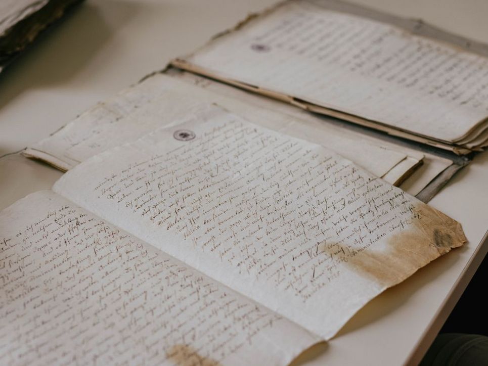Historische handschriftliche Dokumente auf Papier, ausgebreitet auf einem Tisch