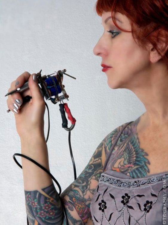 Vyvyn Lazonga im Profil, sie hält eine Tätowiermaschine in der Hand.