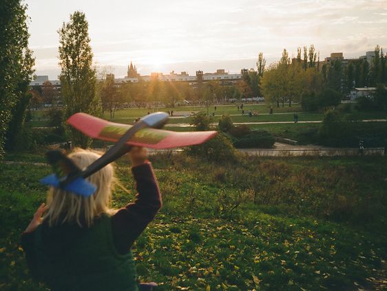 kleines Mädchen lässt ein Spielzeugflugzeug über ein Feld fliegen