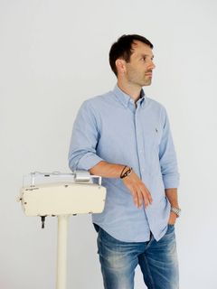 André Kleinridders, einen Arm auf einen Waage gelegt.