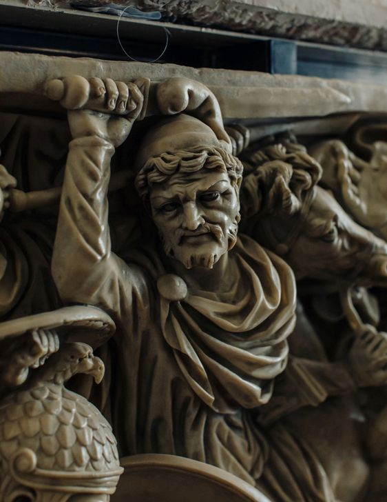 Nachdenklich blickende Steinskulptur, die Teil eines Freskos ist.