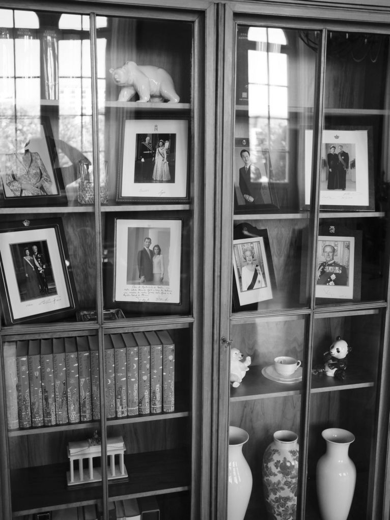 Vitrine mit Fotos von Würdenträgerinnen und Würdenträgern, einem weißen Bären aus Porzellan, einer Vase und Büchern.