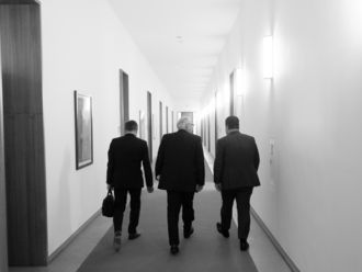 Wilhelm Bauer, Matthias Kleiner und Hubertus Klein gehen einen Flur entlang. Man sieht sie von hinten.