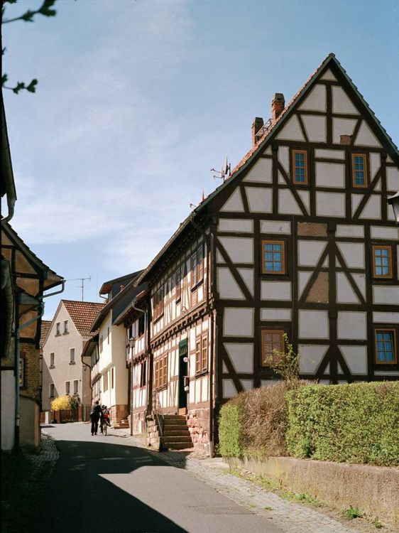 Fachwerkhaus und Menschen auf einer Dorfstraße.