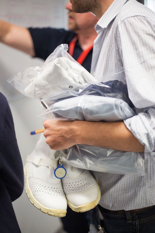 Forscher mit weißer Schutzkleidung und einem Transponder in der Hand.