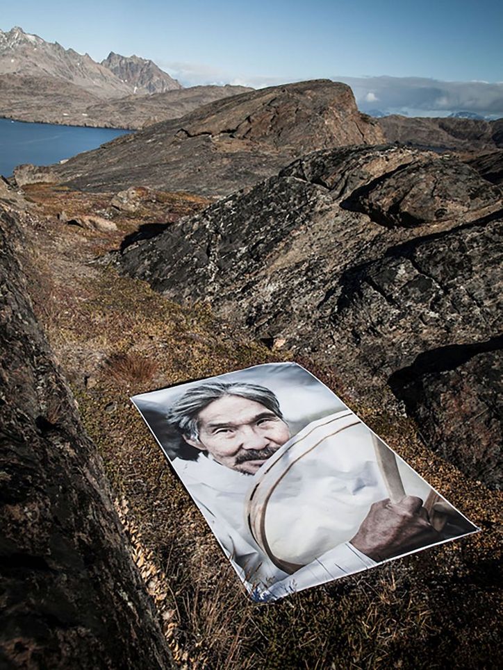 Foto eines Mannes mit Trommel in einer felsigen Küstenlandschaft.