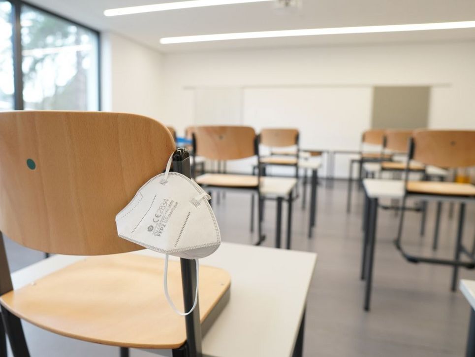 Leeres Klassenzimmer, eine FFP2-Maske hängt an einem Stuhl.