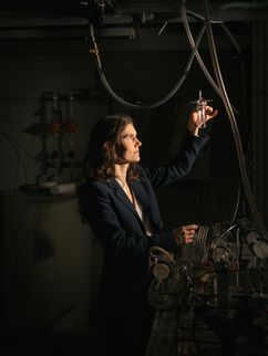 Portrait: Prof. Dr. Mira Pöhlker Die Physikerin Mira Pöhlker schaut auf ein Reagenzglas in ihrer Hand.