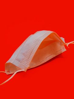 Weiße OP-Maske vor knallrotem Hintergrund.