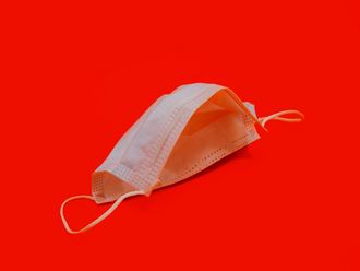 Weiße OP-Maske vor knallrotem Hintergrund.