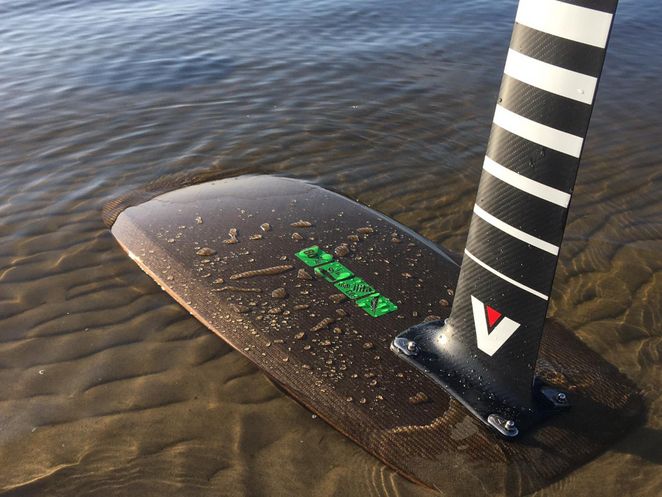 Kiteboard in seichtem Wasser an einem Sandstrand.