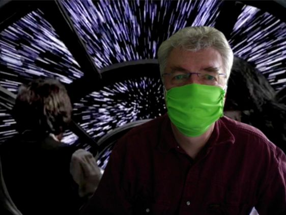 Ein Mann mit grünem Mund-Nasen-Schutz vor einem Sternenhintergrund.
