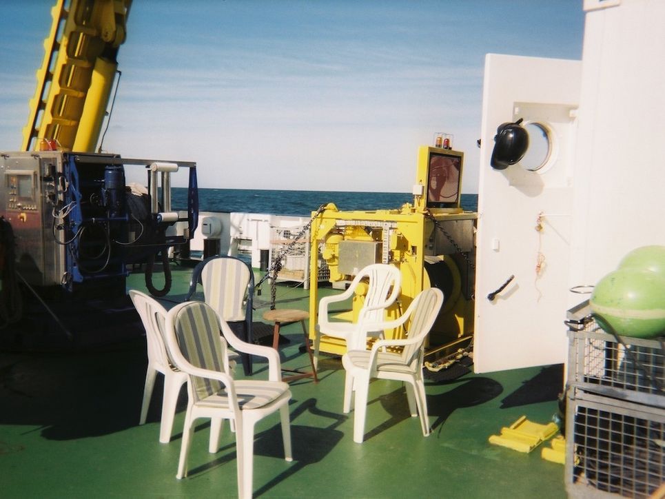 Weiße Plastikstühle auf dem sonnigen Deck.