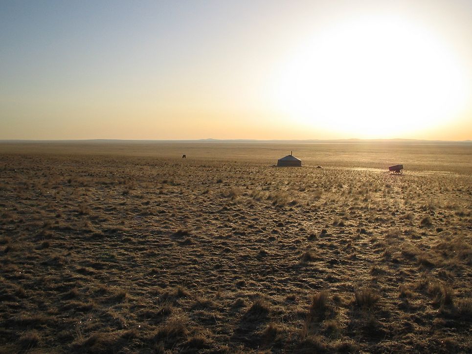 Jurte, Wagen und Pferd in der Ferne bei Sonnenaufgang in der Steppe.
