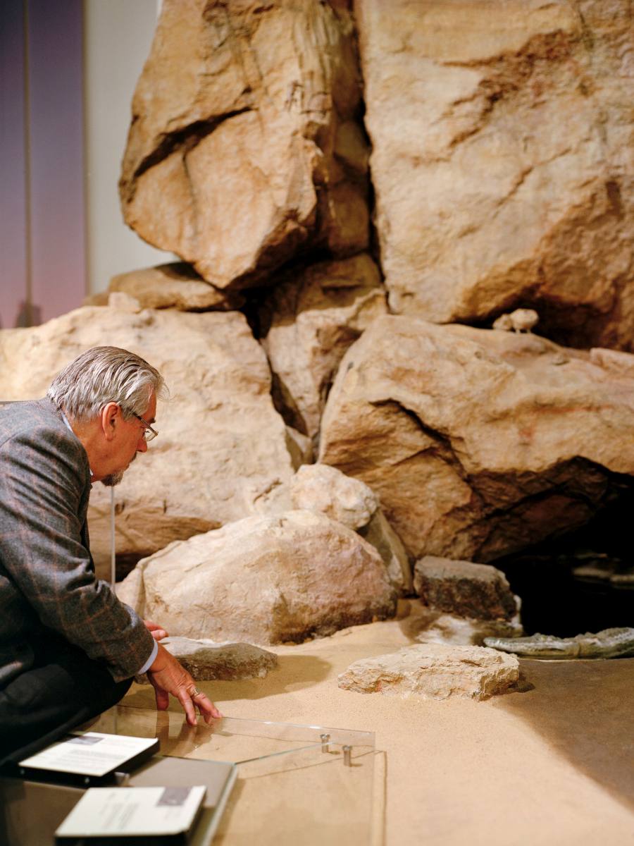 Wolfgang Böhme kniet vor einer steinernen Höhle