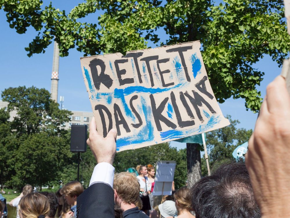 Demonstrierende auf einer Fridays for Future Demo. Ein Plakat mit der Aufschrift "Rettet das Klima" wird in die Höhe gehalten.