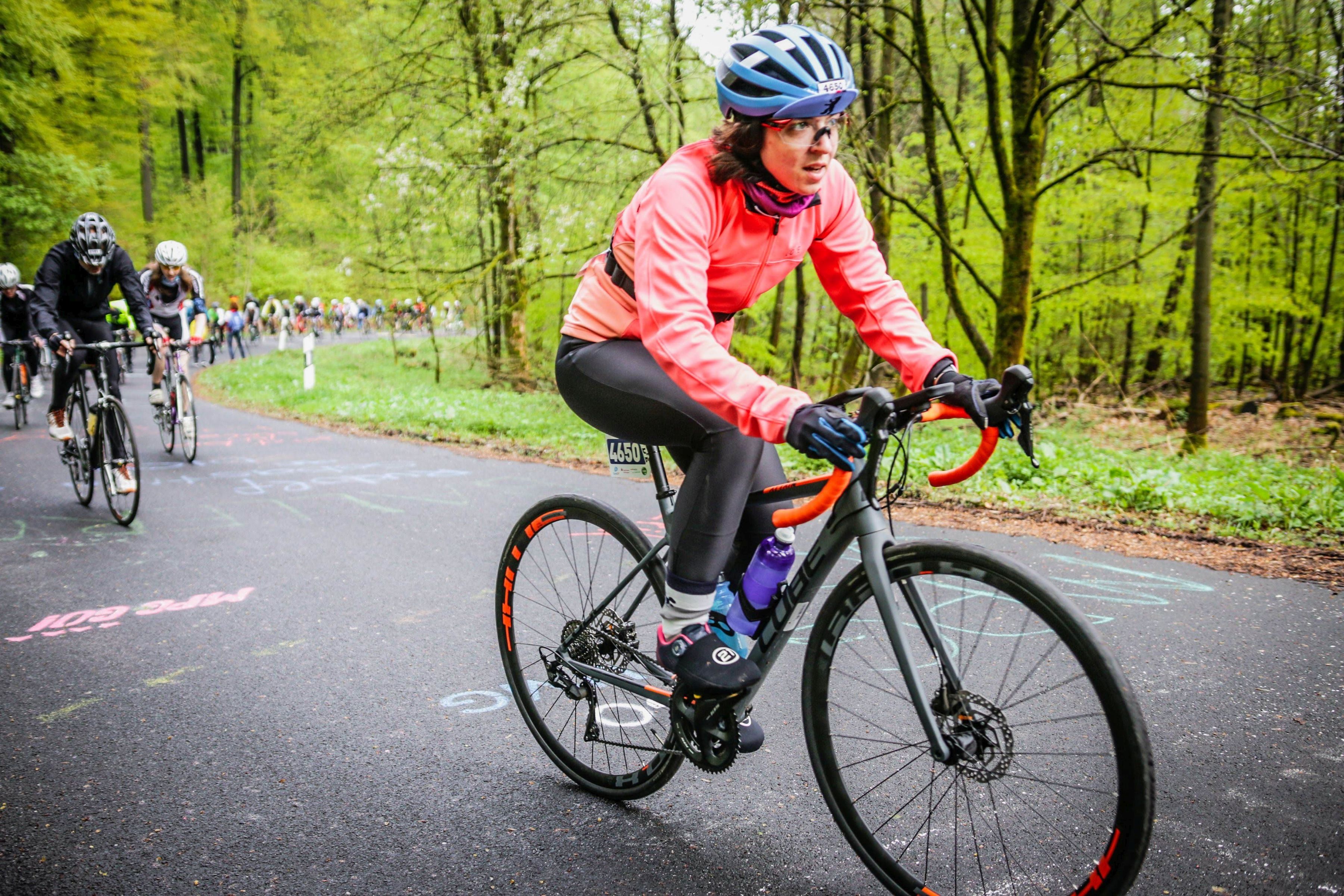 Rennradfahrerin im Wald, hinter ihr einen ganze Kolonne.