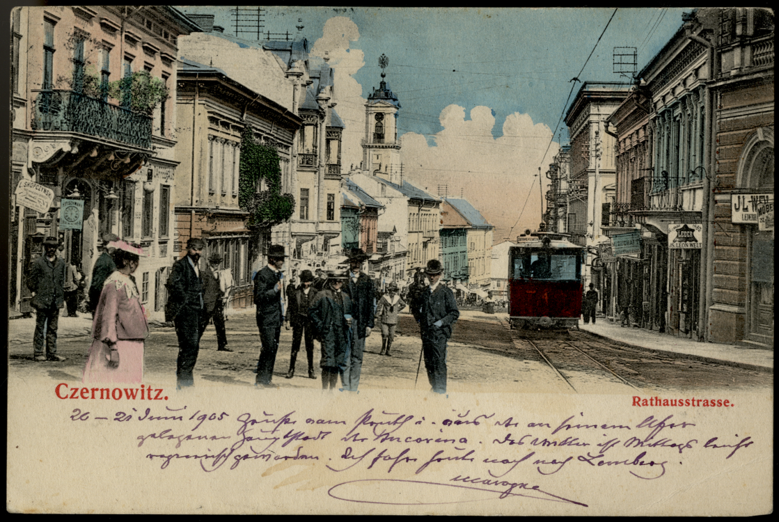 Ansichtskarte mit der Aufschrift Czernowitz, Rathausstraße. Sie zeigt nobel gekleidete Menschen in der Innenstadt sowie eine Straßenbahn. Die Karte ist vorne mit einer handschriftlichen Nachricht versehen.