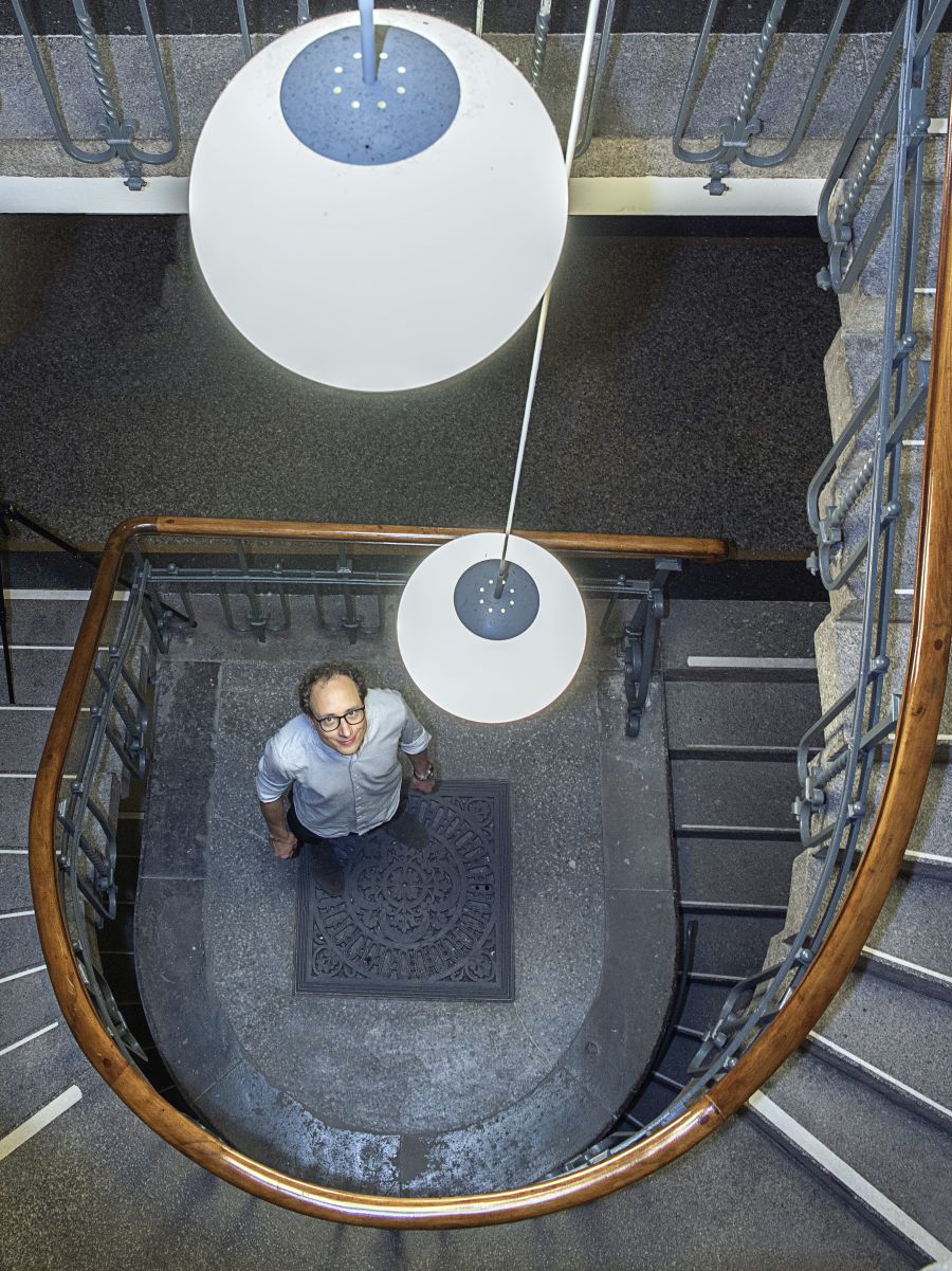 Robert Luther steht im Treppenhaus des MfN, sein Blick folgt den Lampen, die wie Planeten von der Decke schweben.