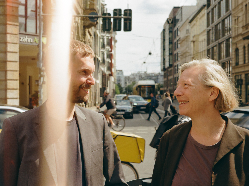 David Schelp und Henriette Löwisch im Gespräch vor einer belebten Straßenkreuzung.