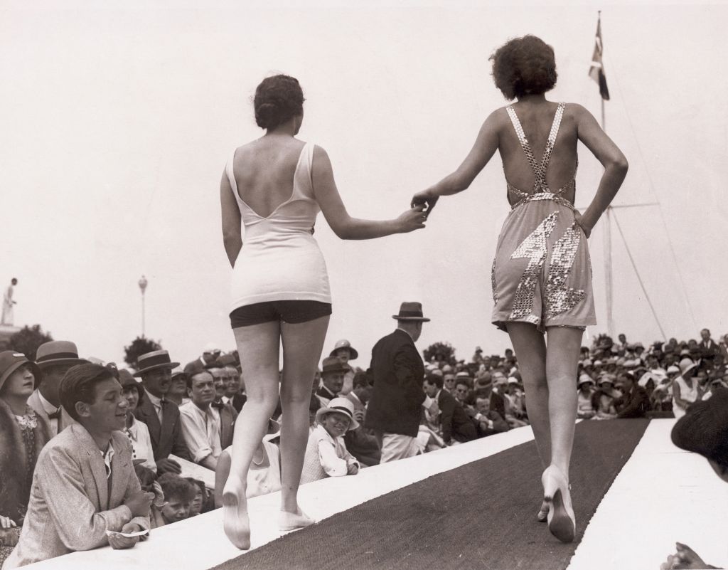 Miss Europa und Miss Amerika laufen 1929 gemeinsam als Miss Universe über einen Laufsteg im Freien. 